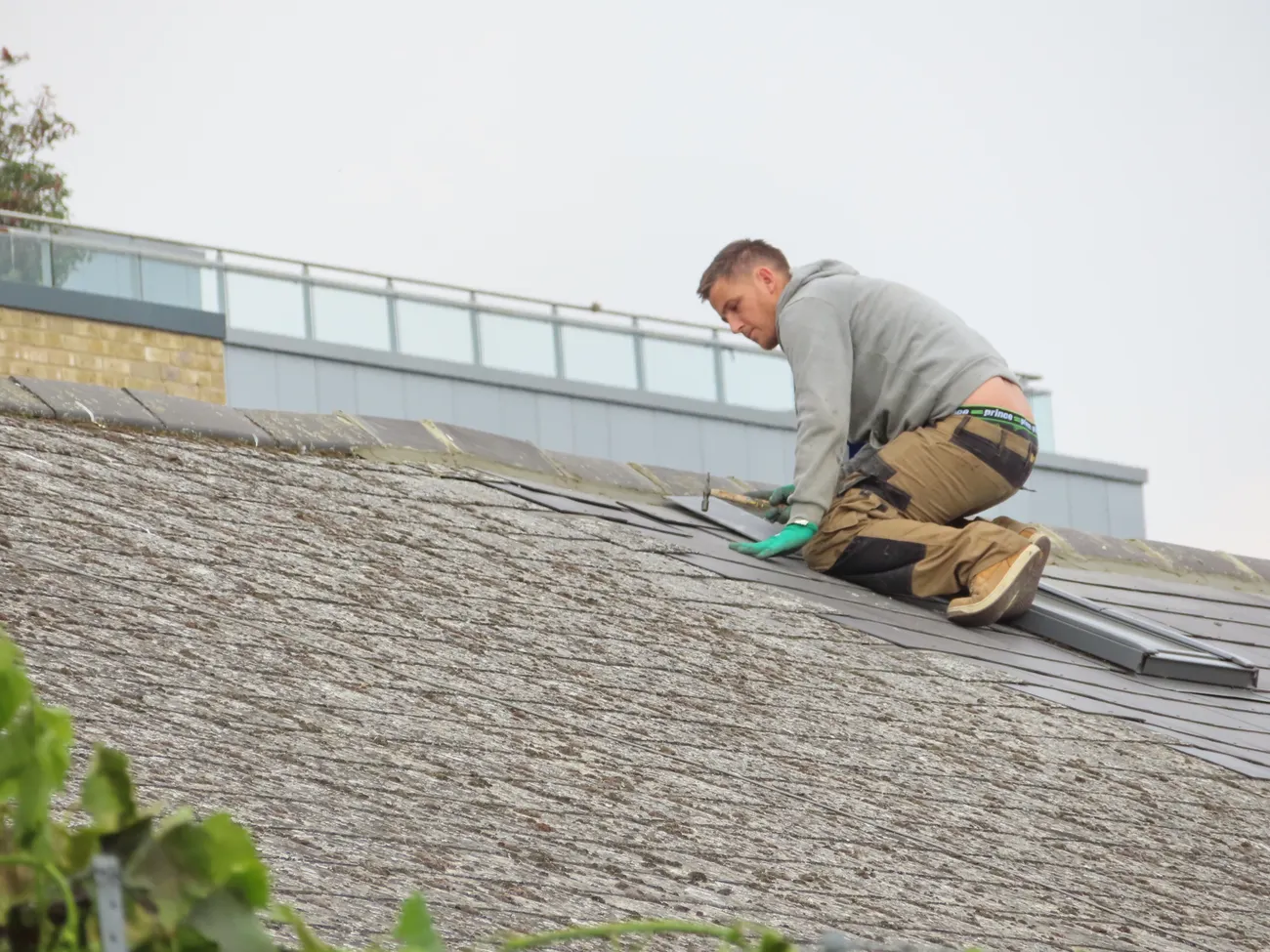 Worker placing roof tiles on a sloped roof